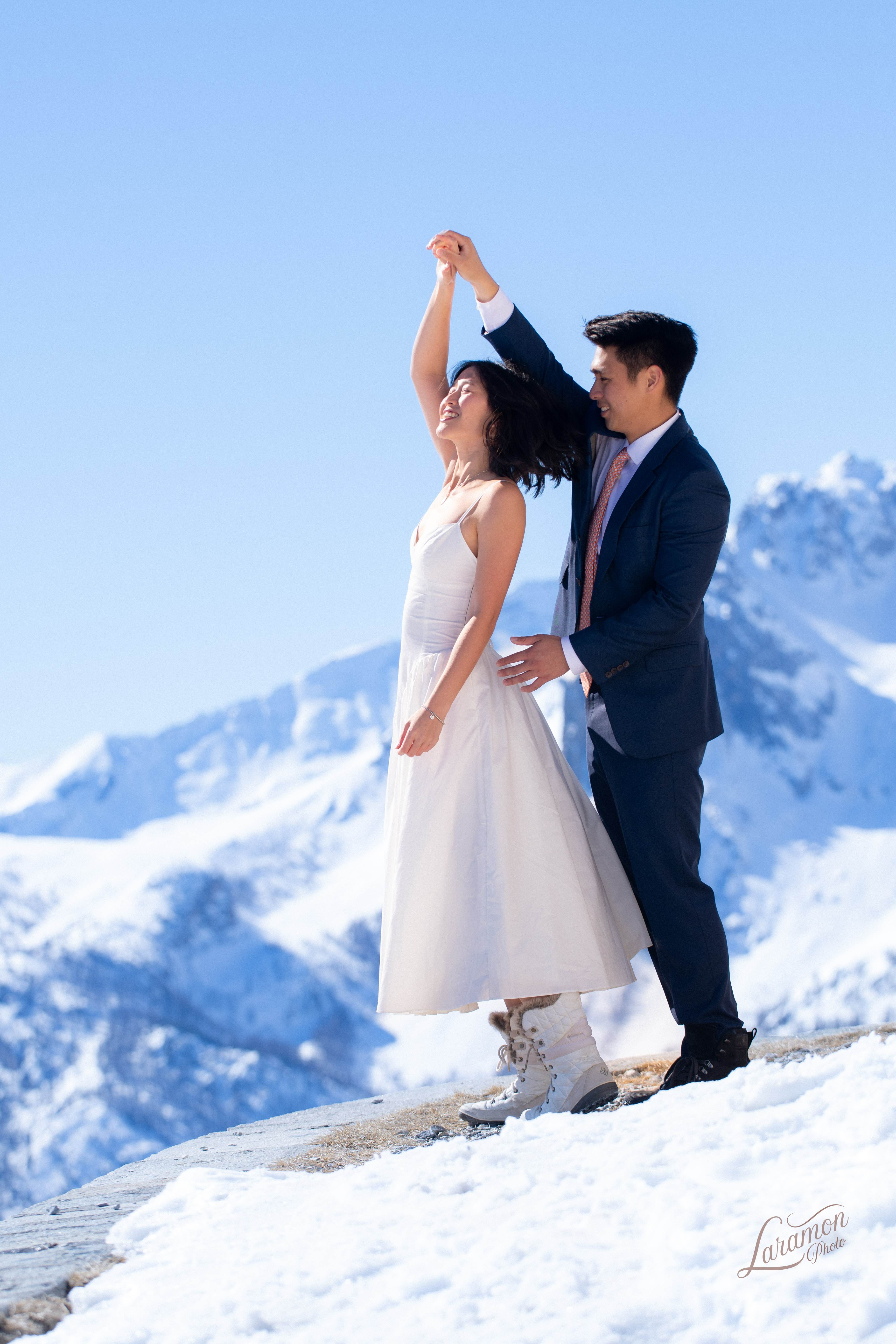 Couple de mariés dansant sur un sommet enneigé